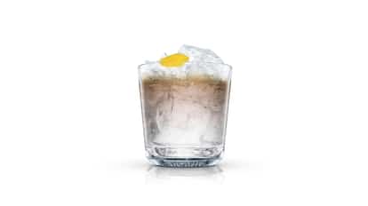 Russian Expresso served in an Absolut rocks glass with crushed ice and lemon peel on white background.