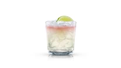 Spicy Mule in an Absolut rocks glass with crushed ice and lime wedge on white background.