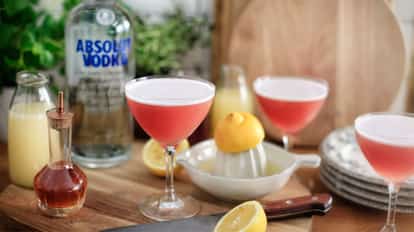 Stairs Martini in three coupe glasses, lemon half on reamer and an Absolut Vodka bottle in the background