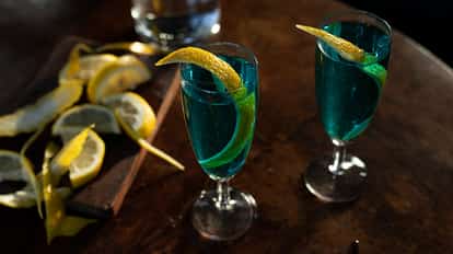 Strong Arm in two champagne flutes with lemon twists on a wooden table