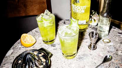 Summer Love in two highball glasses with ice and starfruit garnish and an Absolut Citron bottle on marble