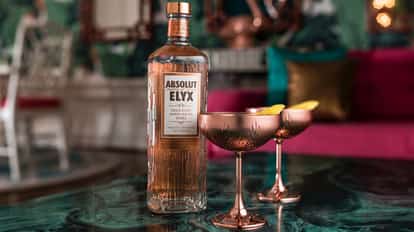 The Elyx Martini served in two coupe glasses with lemon twists and an Absolut Elyx bottle on a table