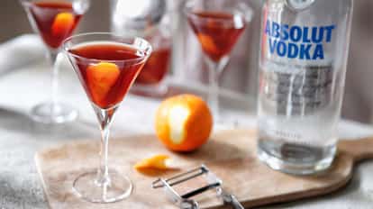 Yankee-dutch in a stemmed martini glass with orange twist and Absolut Vodka bottle on a wooden board